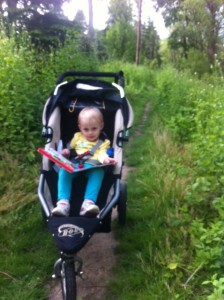 2 year old in jogging stroller, reading a musical book